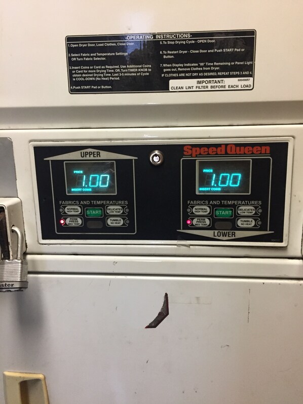 A Speed Queen dryer with digital displays for upper and lower settings, fabric and temperature controls, and a lockable door.