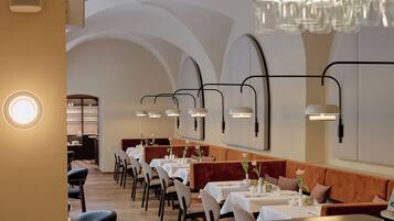 Un restaurant avec de longues tables, des banquettes confortables et un éclairage moderne suspendu au plafond.