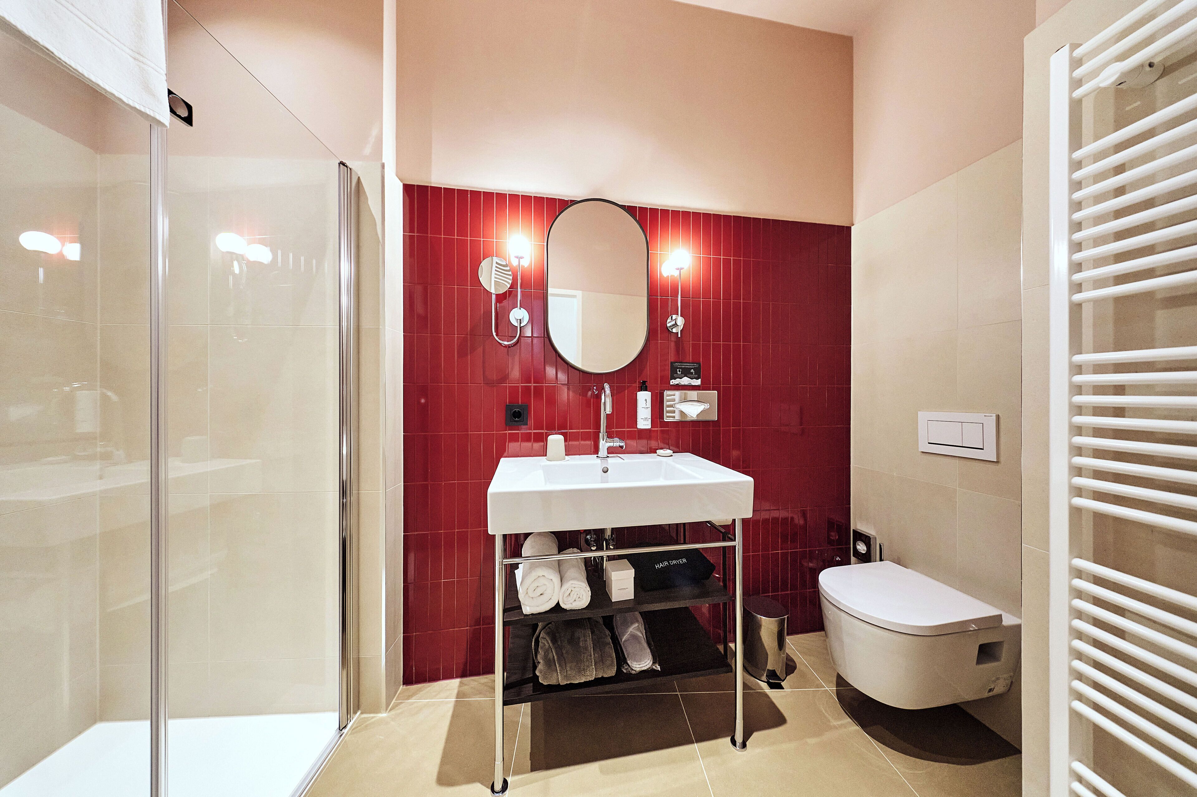A modern bathroom with a glass shower enclosure, a white sink with a mirror above, and a toilet with a towel rack.