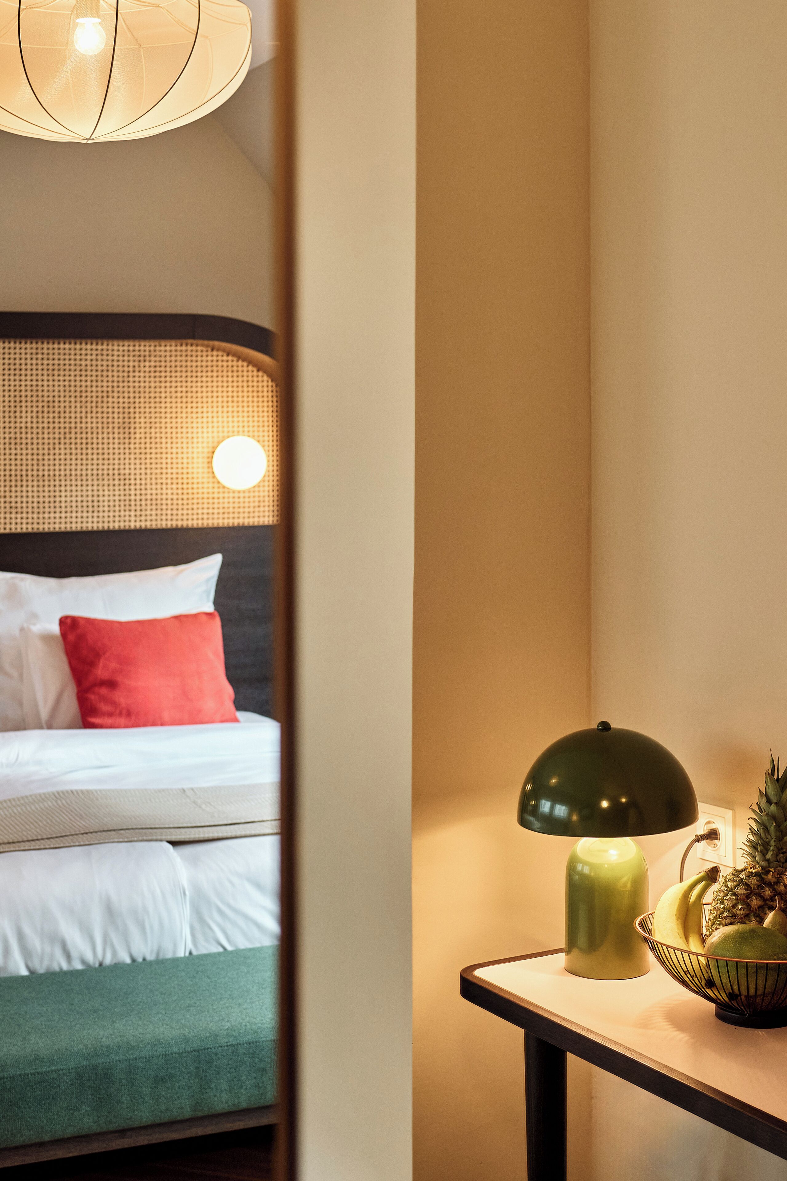 A hotel room with a bed, a nightstand, a lamp, and a fruit bowl.