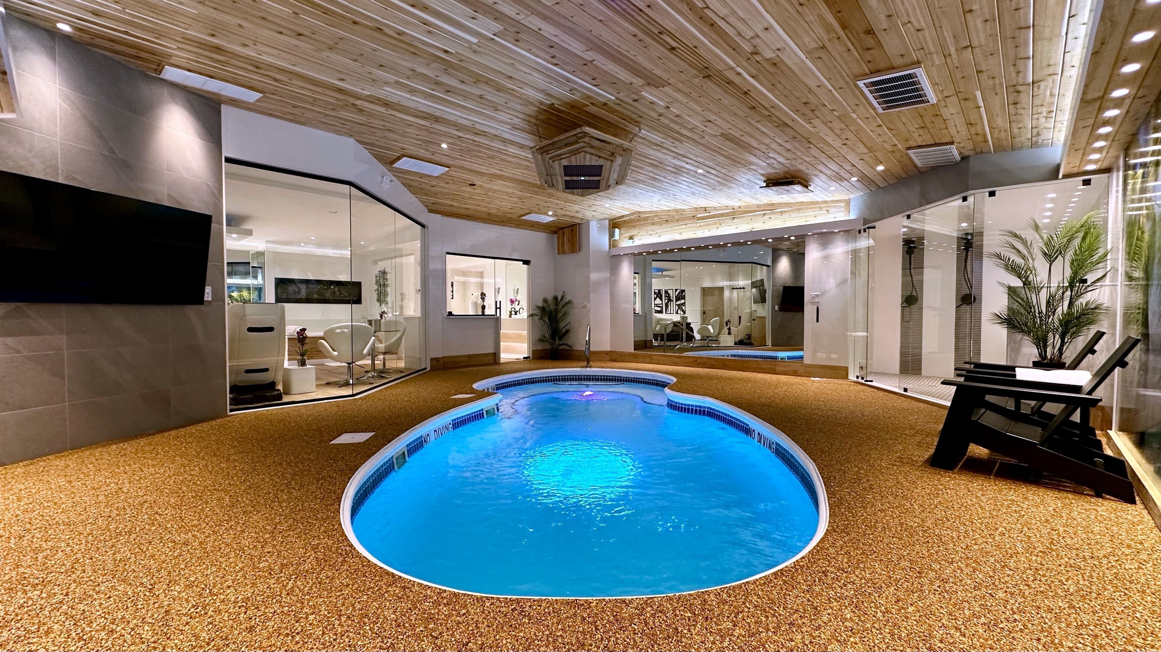 Una piscina interior con techo de madera y suelo de baldosas.