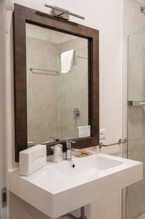 A bathroom with a white sink, a mirror with a wooden frame, a towel rack, and a glass shower enclosure.