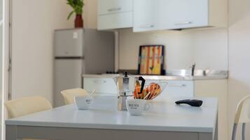A modern kitchen with white cabinets, a coffee maker, and a fruit bowl on the counter.