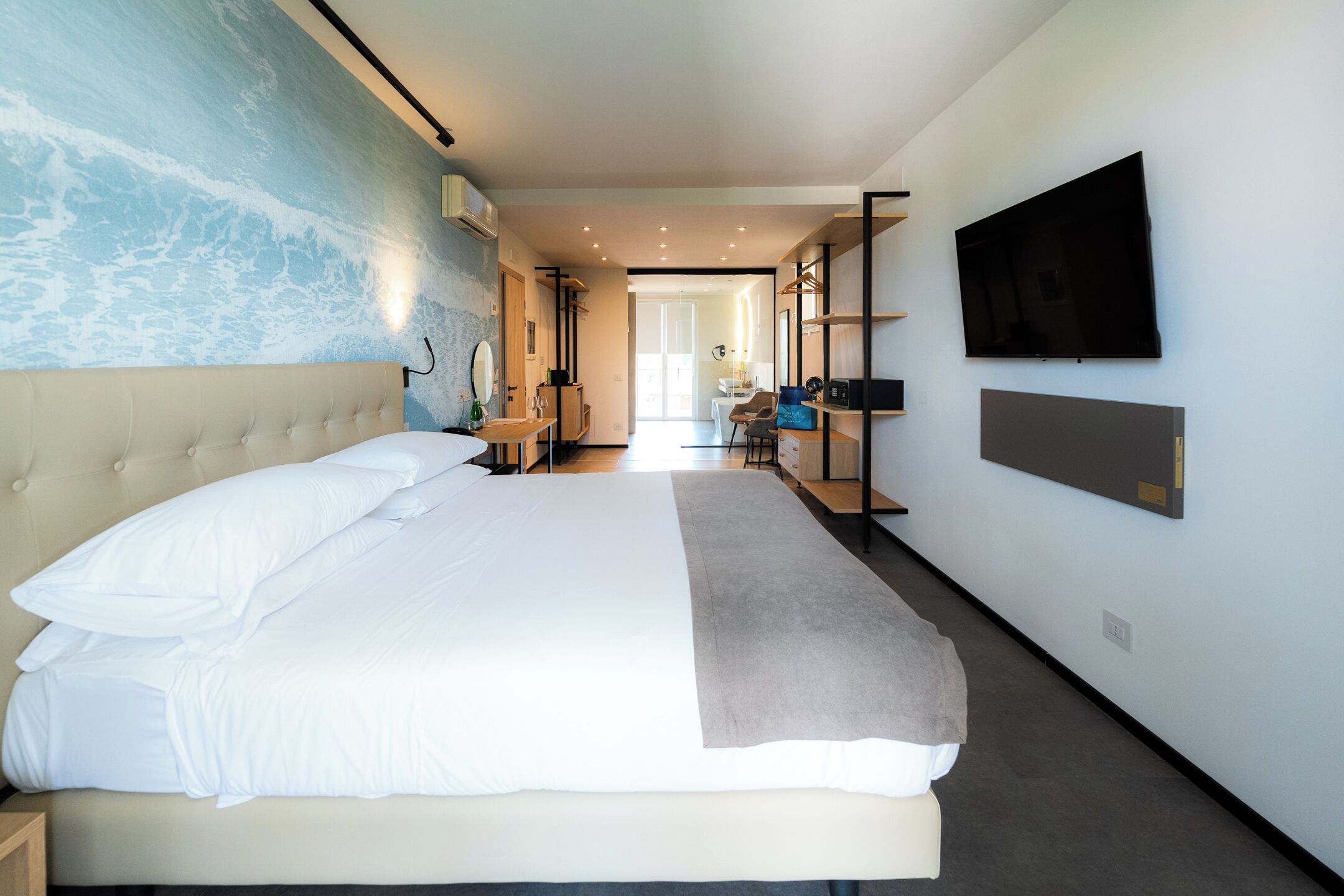 Ett modernt hotellrum med en stor säng, en platt-TV som är monterad på väggen och utsikt över korridoren.