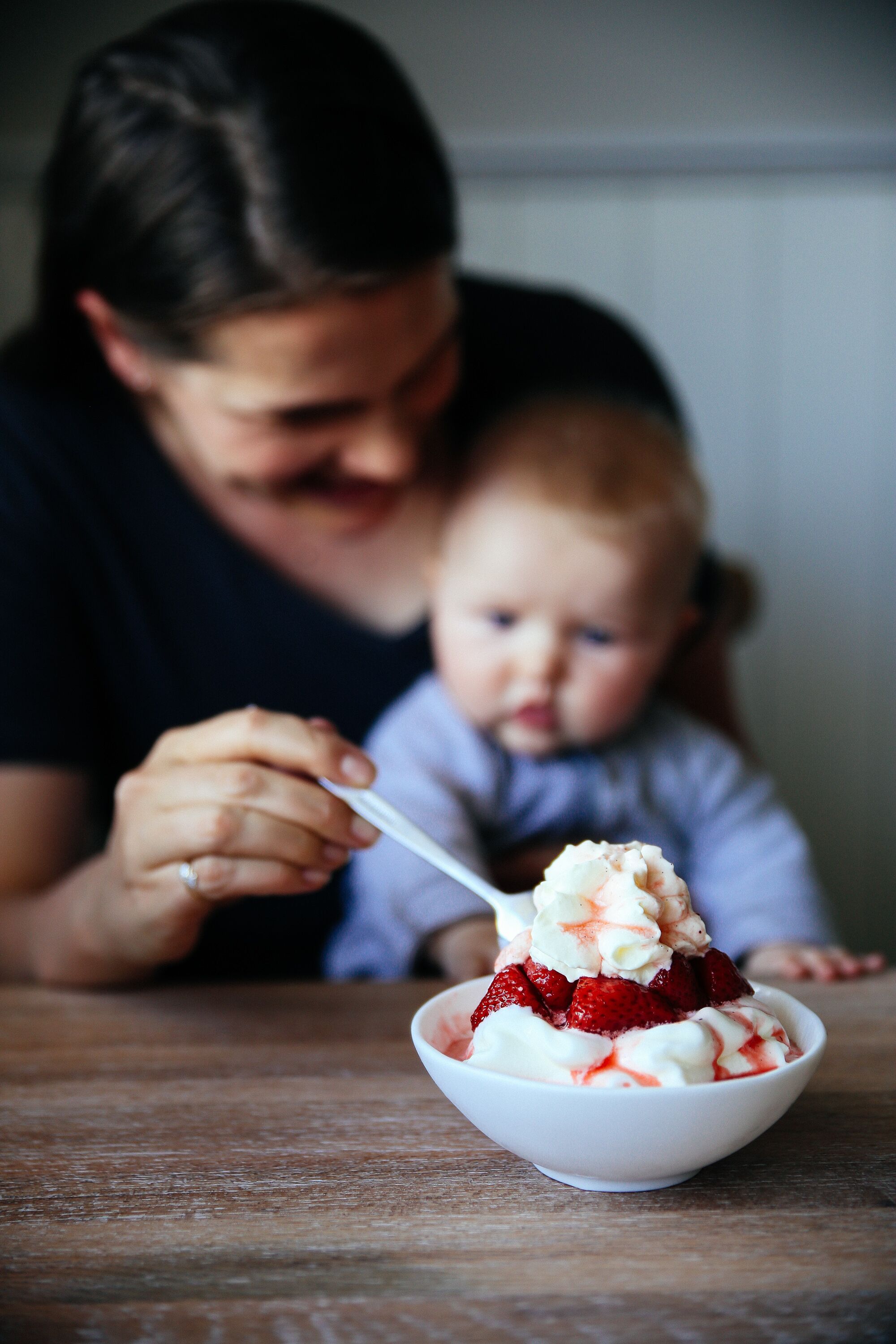 A bowl of dessert with strawberries and whipped cream.