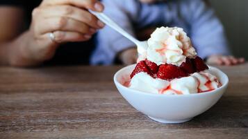 A bowl of dessert with strawberries and whipped cream.