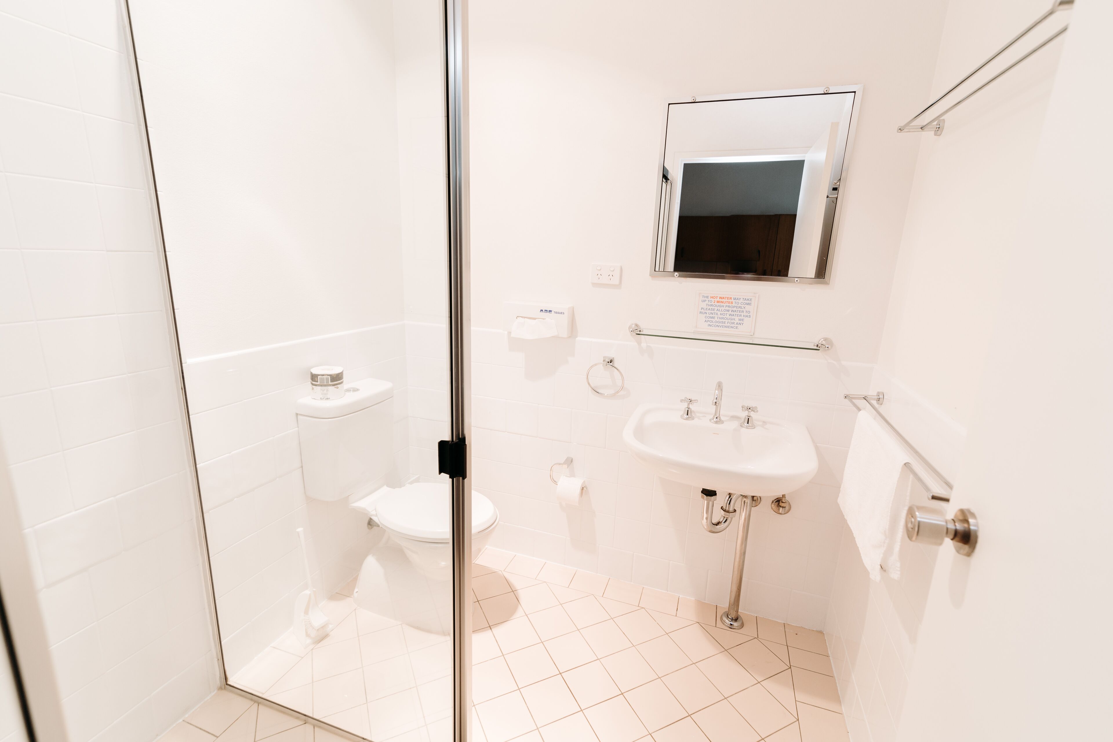 A bathroom with a glass shower enclosure, a toilet, a sink, and a mirror.