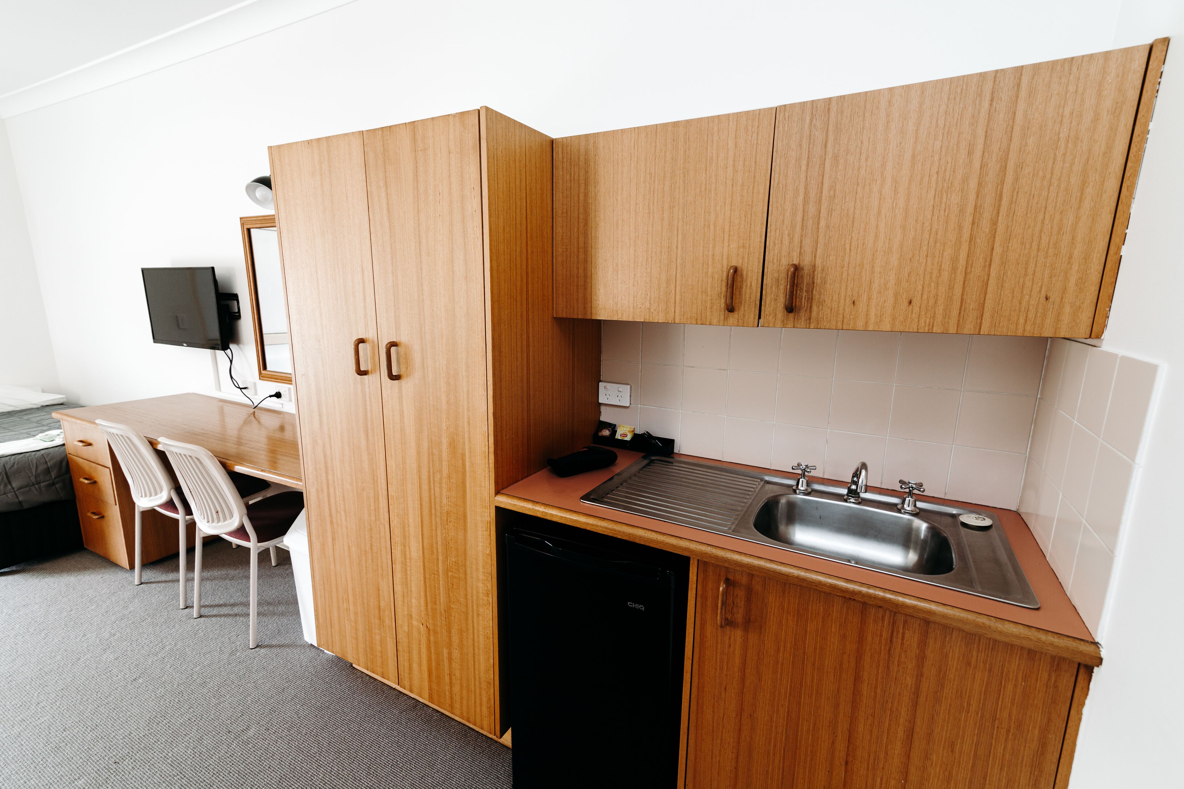 Cocina compacta con muebles de madera, lavavajillas integrado y un lavamanos.