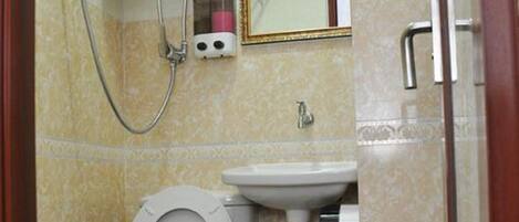 A bathroom with a toilet, sink, and a shower unit.