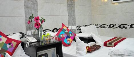 A hotel room with a bed, bedside table, lamp, and a TV mounted on the wall.