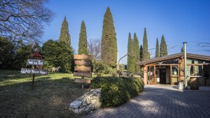 A welcoming sign with multilingual greetings, a stone wall, and a building entrance with a wooden roof. - Corte San Mattia - Agriturismo in Verona (Verona)
