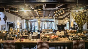 A rustic café interior with wooden tables, checkered tablecloths, hanging lights, and various food items displayed on the tables. - Corte San Mattia - Agriturismo in Verona (Verona)