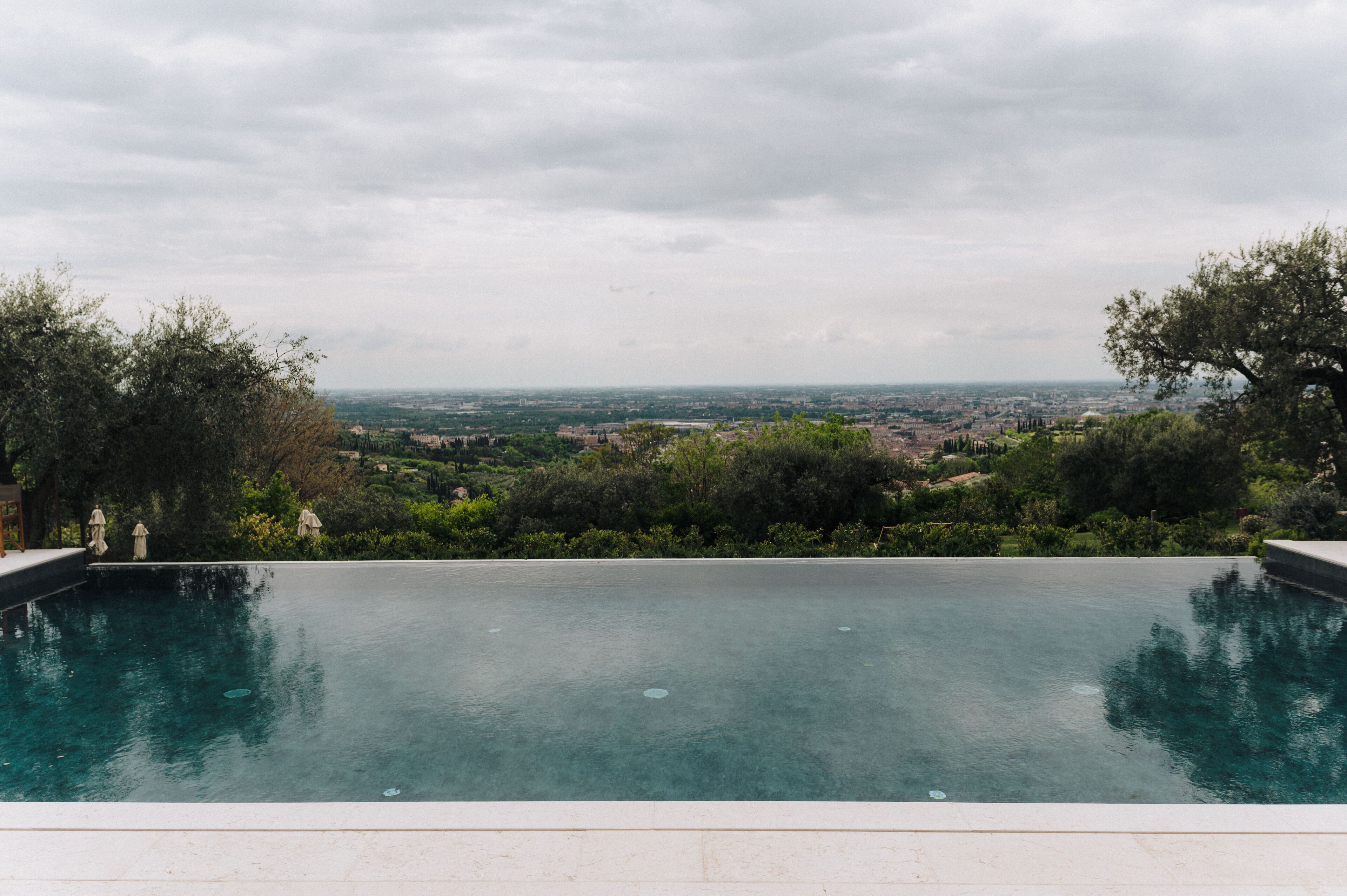 An infinity pool with a view of a cityscape and greenery.