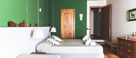 A bedroom with two beds, a wooden door, a dresser, and a green wall.