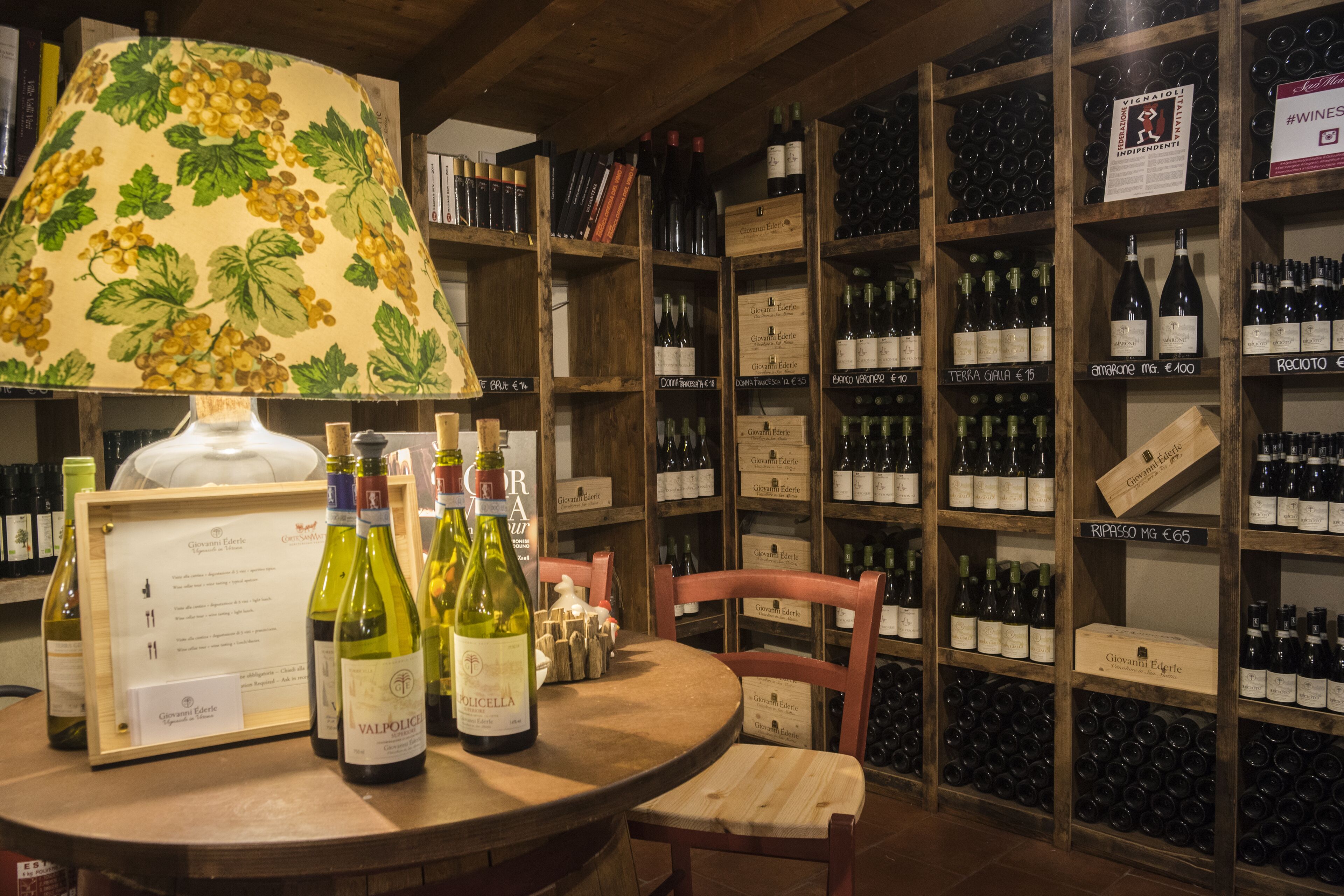 Ein Weinkeller mit Holzböden, gefüllt mit Weinflaschen, ein Tisch mit einer Weinkarte und ein hölzerner Stuhl.