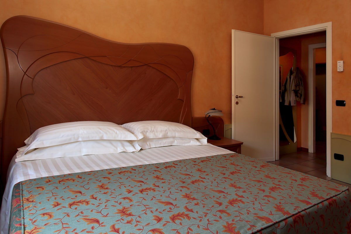 Una cama con cubrecama floral y cabecera de madera.