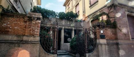 A narrow alleyway with a wrought iron gate leading to a building entrance.
