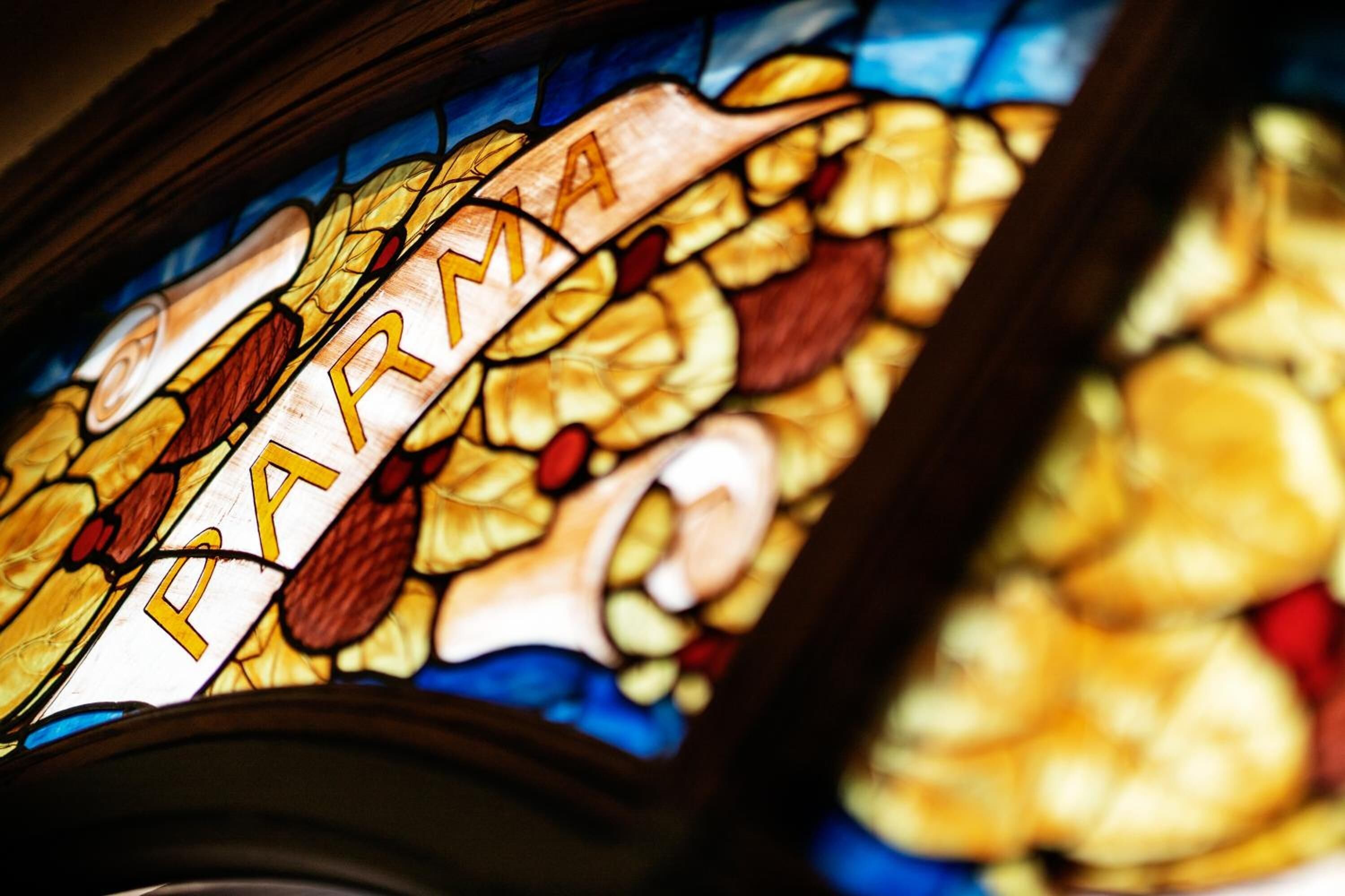 A stained glass window with the word "PARMA" prominently displayed.
