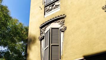 A building with a yellow facade, ornate window shutters, and decorative moldings.