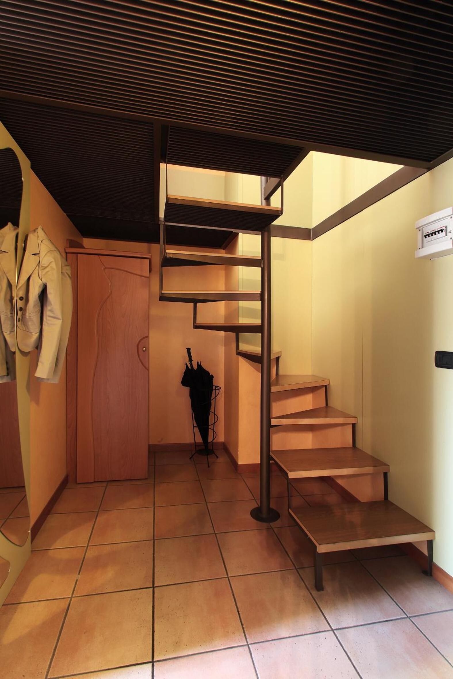 Una escalera con detalles de madera, un perchero con una chaqueta y una puerta.