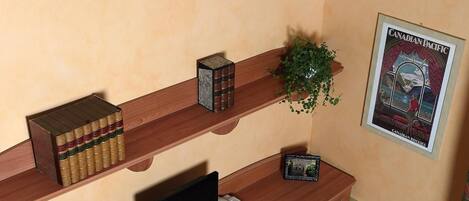 Een kleine studeerkamer met een bureau, stoel en boekenplanken.