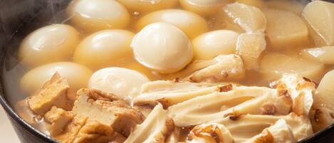 A pot of soup with round, boiled eggs and pieces of meat.