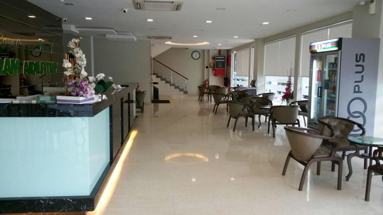 A hotel lobby with a reception desk, seating area, and a staircase leading to another floor.