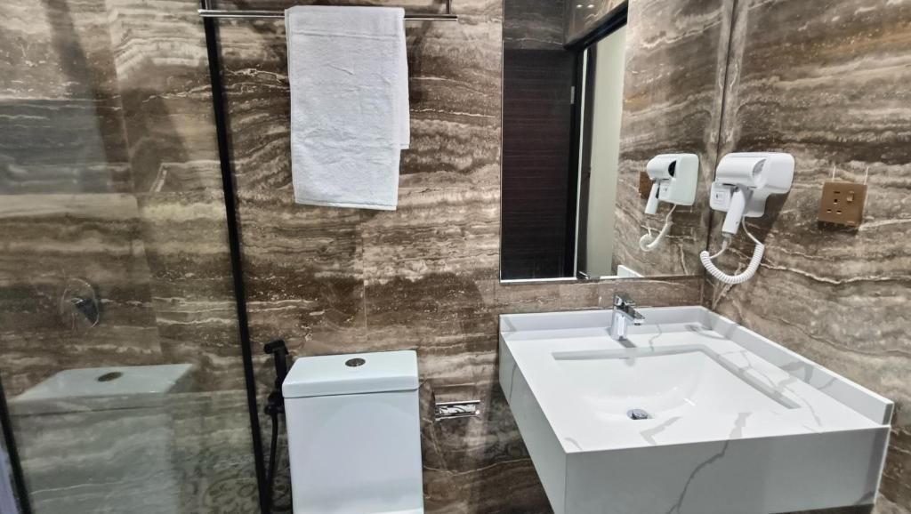 A bathroom with a marble wall, a white sink, and a toilet.