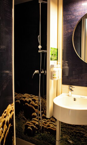 A bathroom with a white sink, a mirror, and a shower.