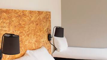 Ein Hotelzimmer mit zwei Betten, einem hölzernen Kopfteil und Nachttischlampen.