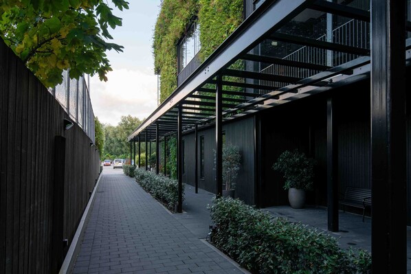 A narrow alleyway with a covered walkway, wooden fence, and greenery. - Hotel & Wellness Zuiver (Amsterdam)