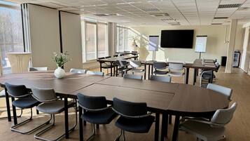 A conference room with a large table, chairs, a projector screen, and a whiteboard.