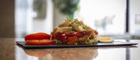 Un sándwich de tomate y huevo sobre una superficie reflectante.