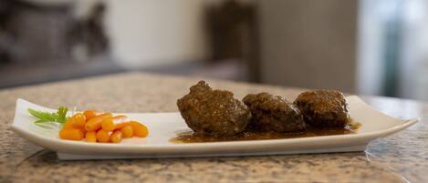 Un plat amb boles de carn i pastanagues damunt un taulell de granit.