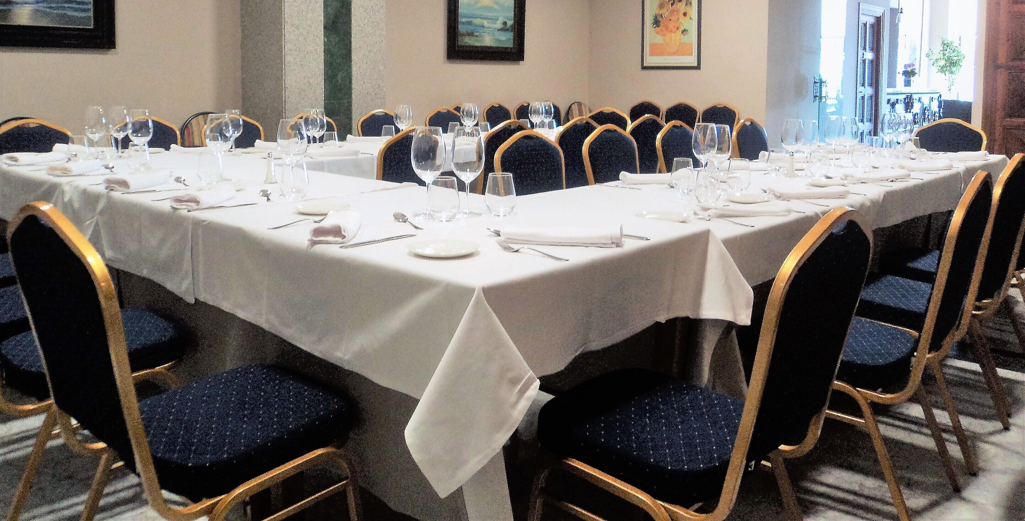 A banquet hall with multiple round tables set for dining, each with chairs and table settings.