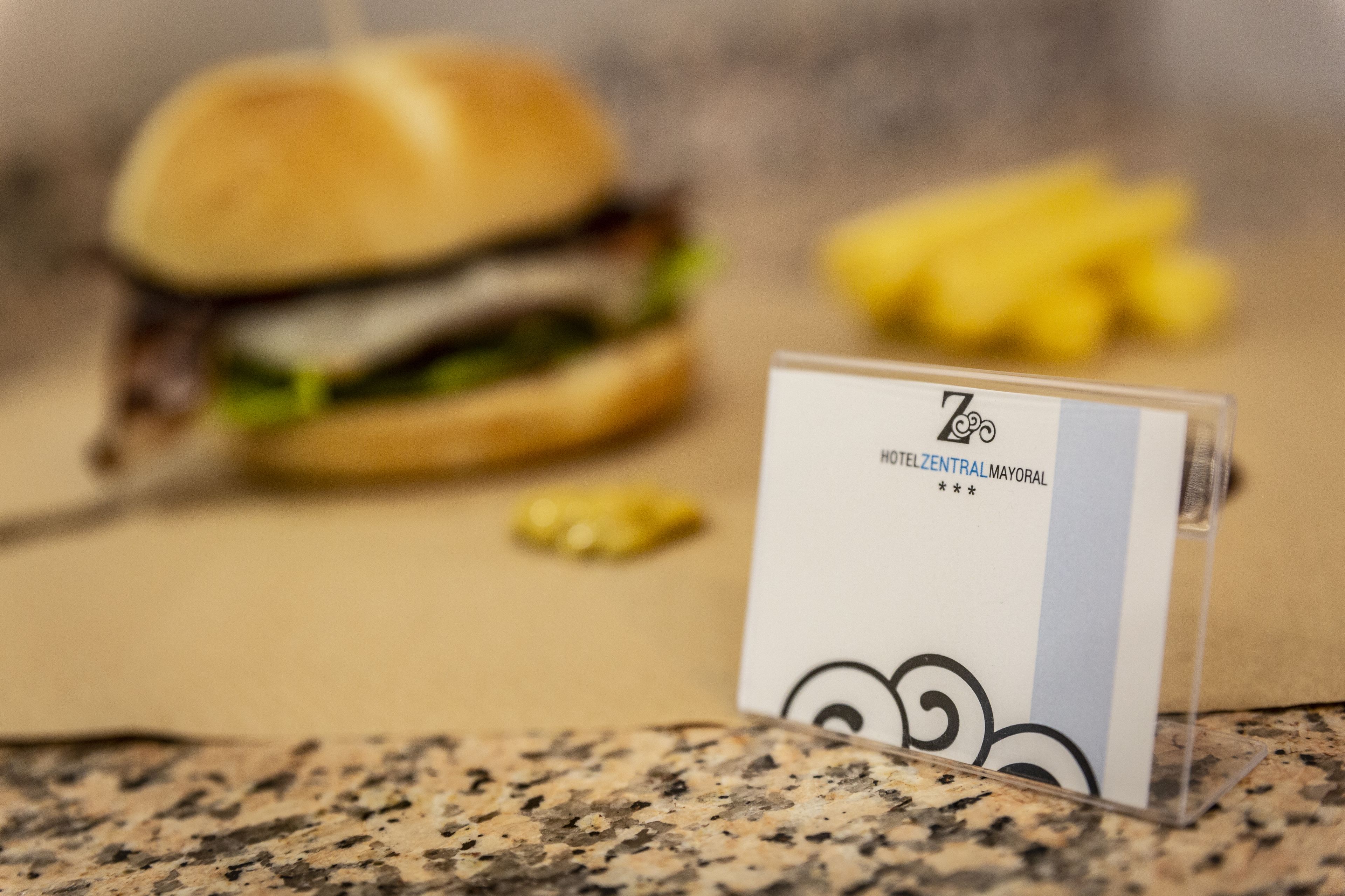 A menu card with the text "HOTELCENTRALMAYORAL" on a clear stand.