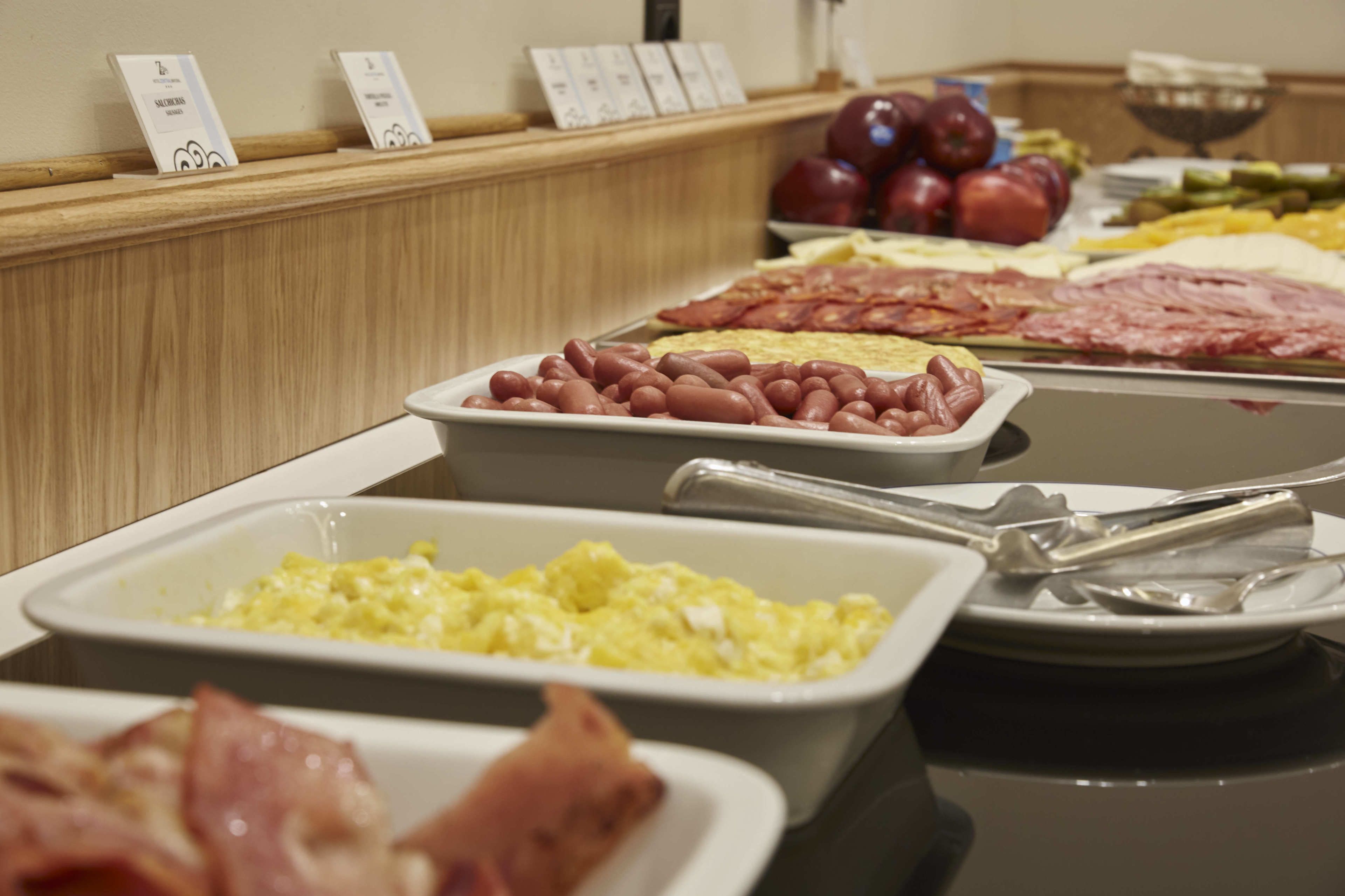 A buffet with various food options including beans, eggs, and meats.