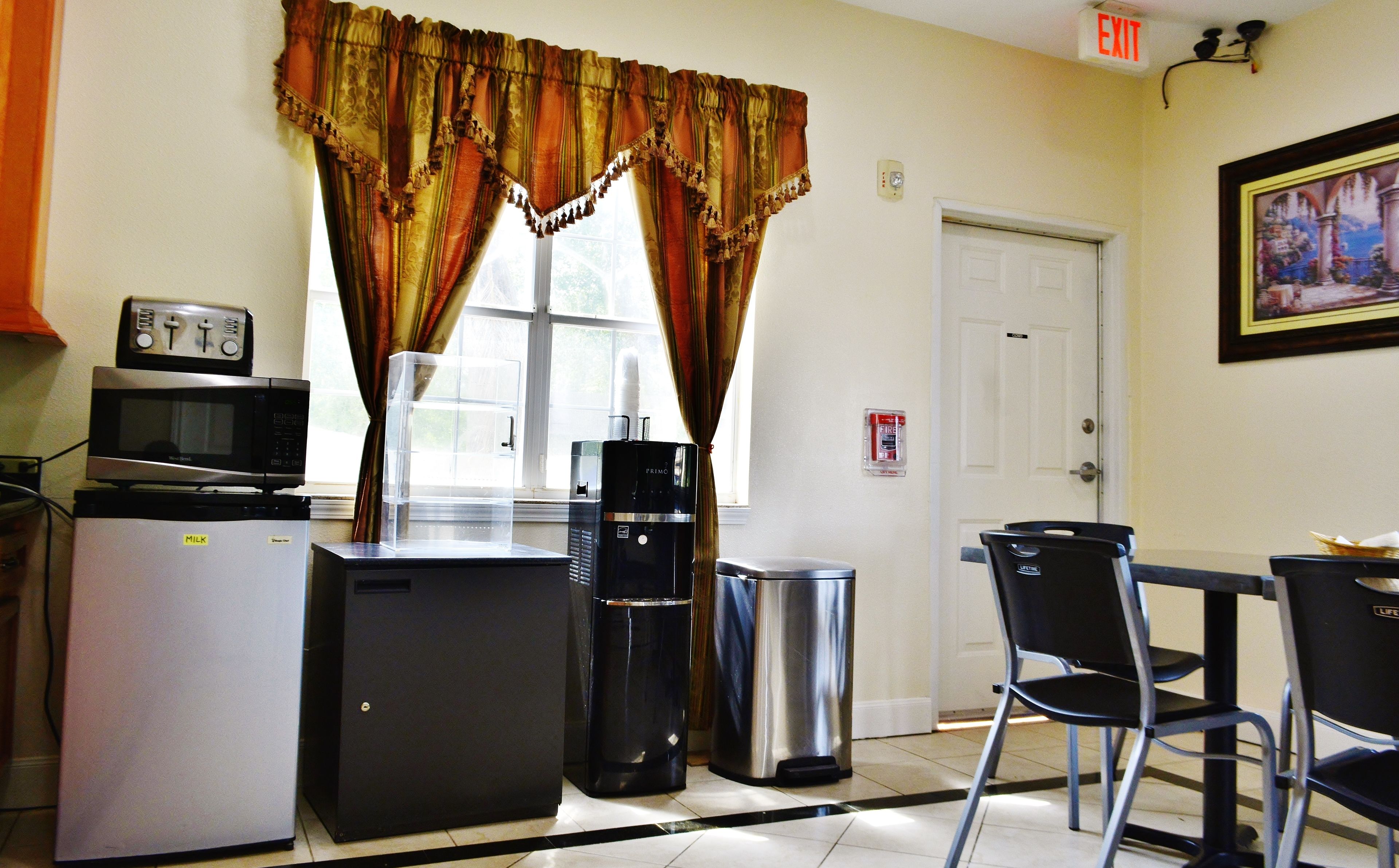 A compact kitchenette with a microwave, refrigerator, coffee maker, and trash bin.