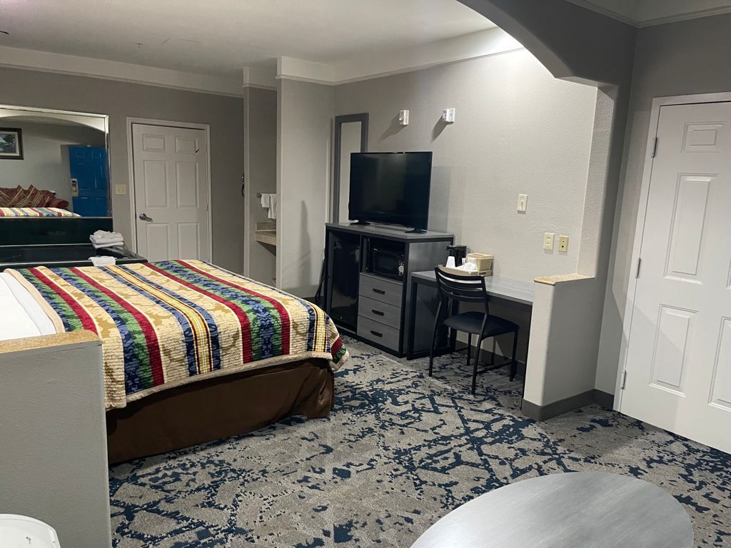 A bedroom with a bed, a desk with a chair, a television, and a wardrobe.