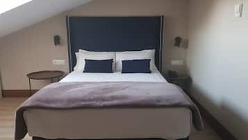 Un dormitorio con cama, una mesita redonda pequeña, una lámpara de noche y un teléfono instalado en la pared.