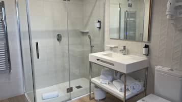 Een moderne badkamer met een douchecabine van glas, een wit wastafelmeubel met spiegel en een toilet.