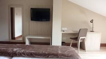 Un dormitorio con cama, escritorio, silla, televisión y espejo.
