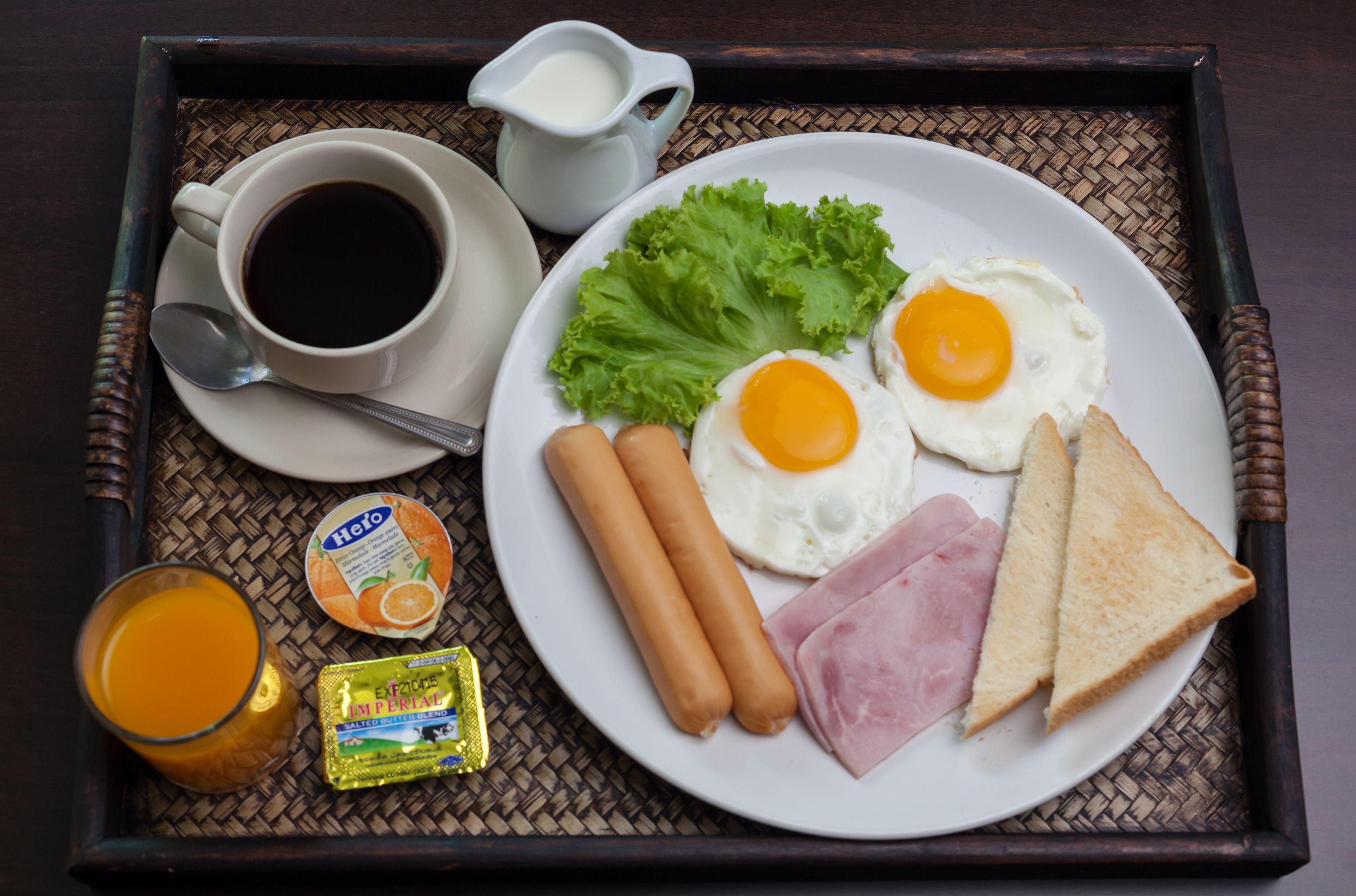 Een ontbijfwagen met eieren, ham, worstdogjes, toast, een kop koffie, een glas sinaasappelsap en een kleine melkkaraffe.