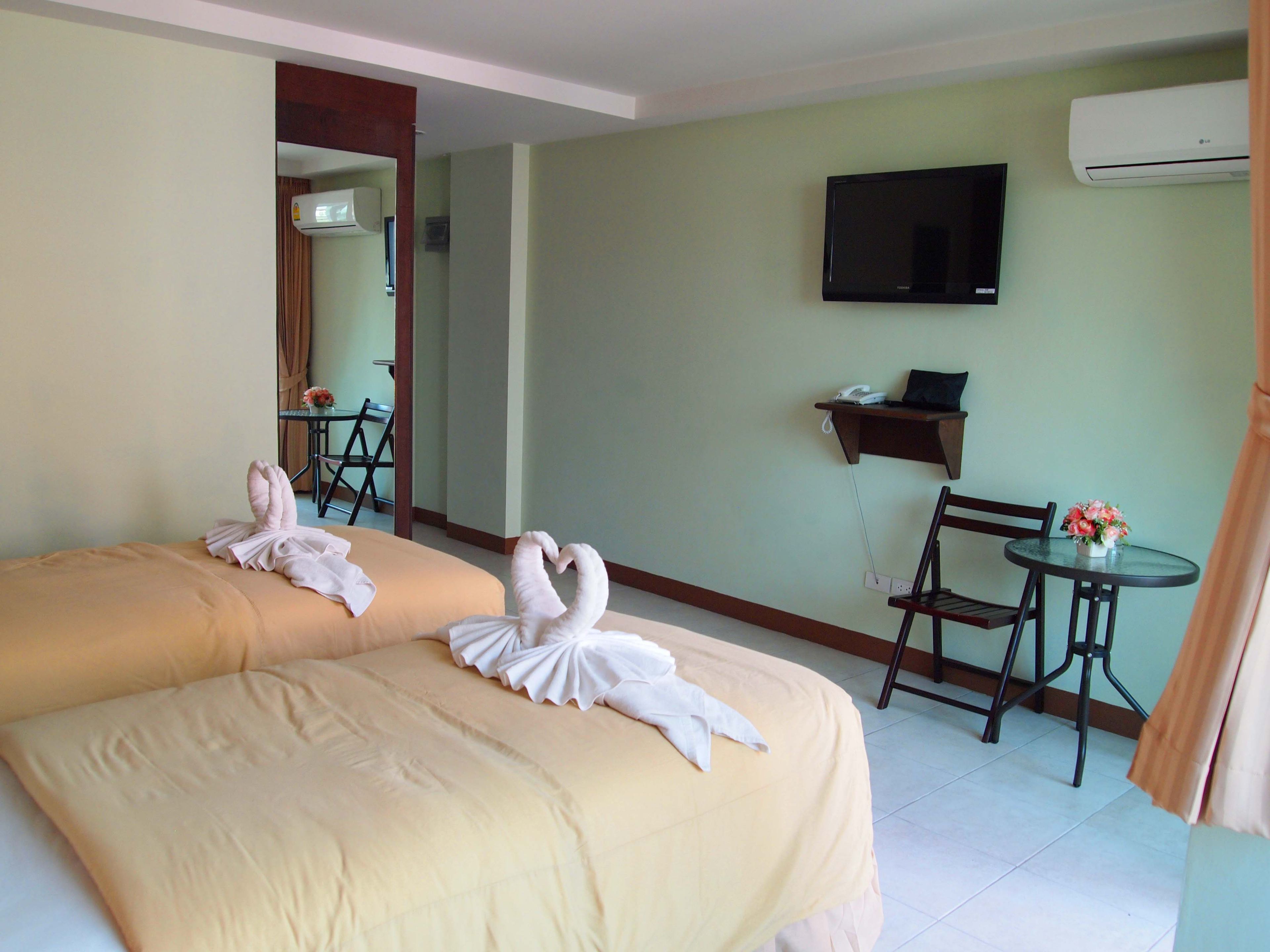 Une chambre d’hôtel avec deux lits, une télévision, un bureau et une chaise.
