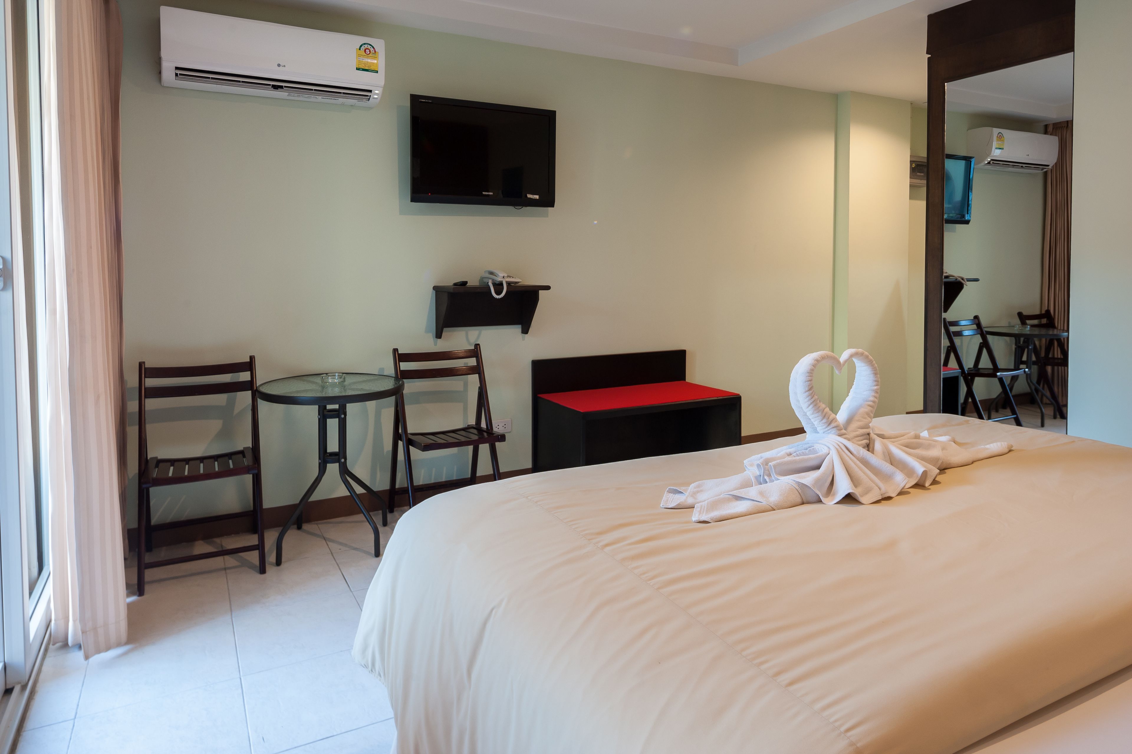 Una habitación de hotel con cama, escritorio, dos sillas, televisor y una mesa roja.