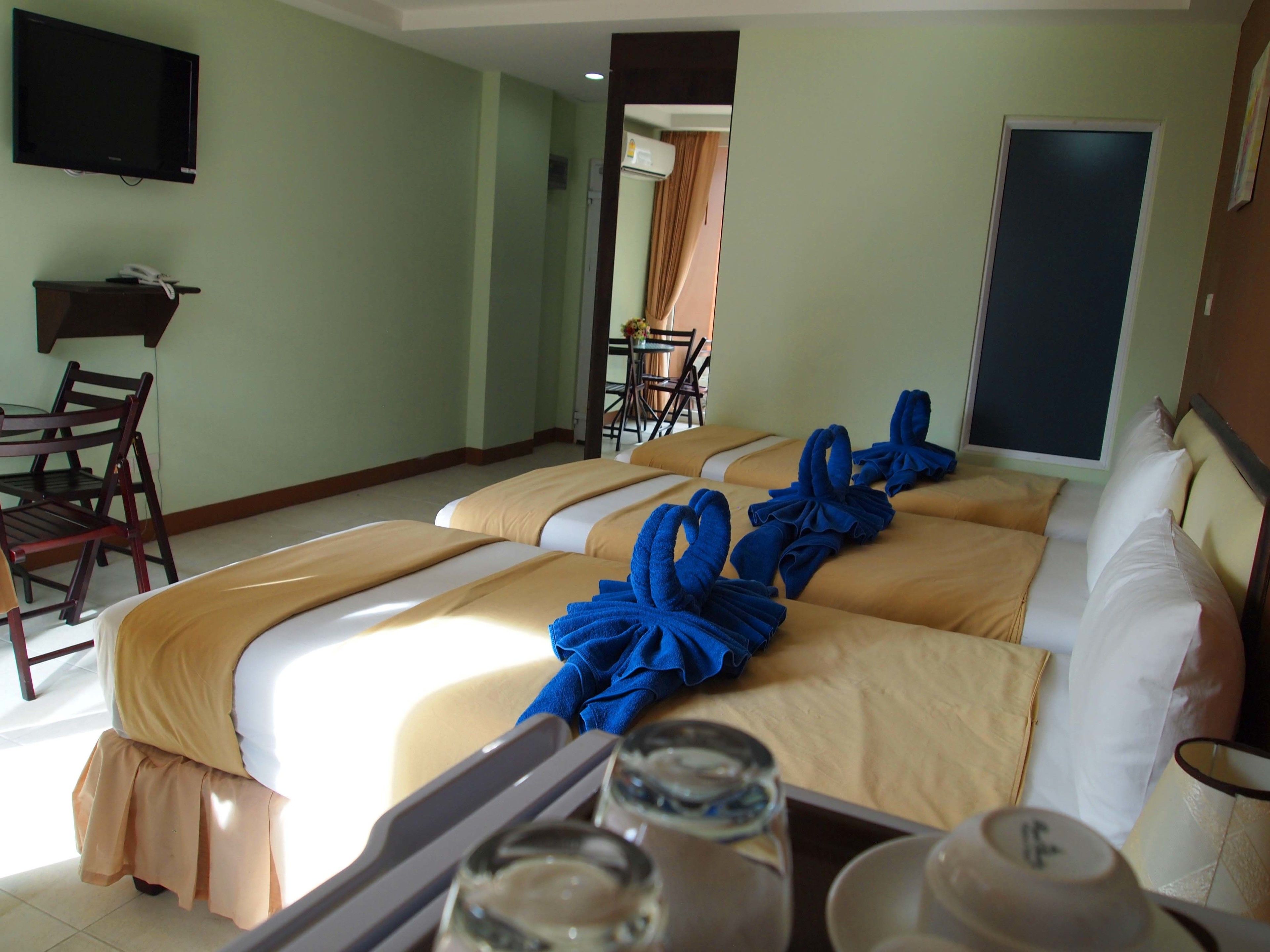 A hotel room with two beds, a TV, a desk, and a chair.