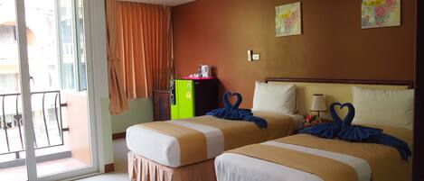 Quarto de hotel com duas camas, porta de correr para varanda, minibar e um quadro na parede.