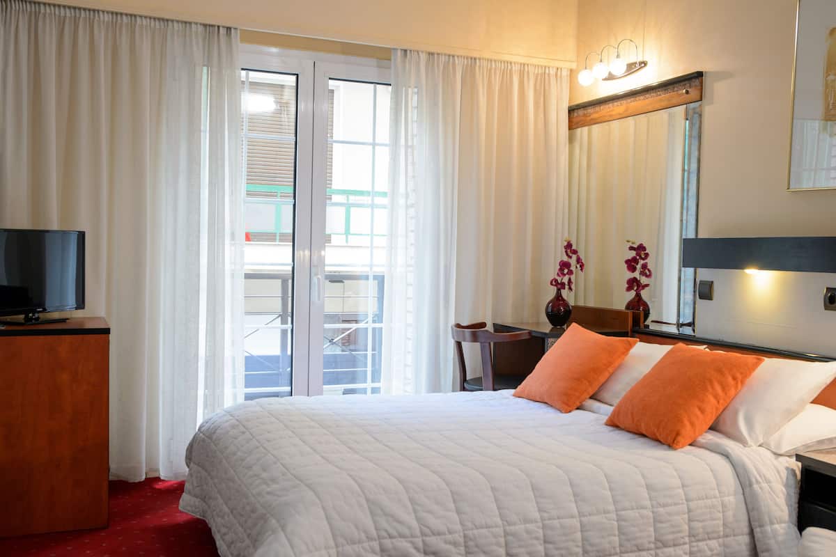 Ein Hotelzimmer mit Bett, Schreibtisch, Stuhl, Fernseher und einem großen Spiegel.