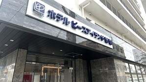 A hotel entrance with a modern facade, featuring a prominent sign and a glass door entrance. - Hotel Peace Island Naha (Naha)