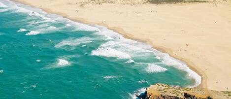A coastal beach with clear turquoise waters and a rocky outcrop.